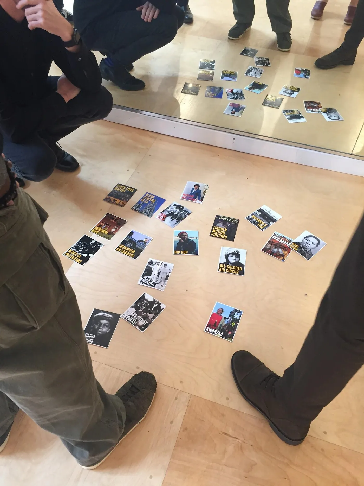 Portrait cards laid out in rows on the floor as participants stand around them