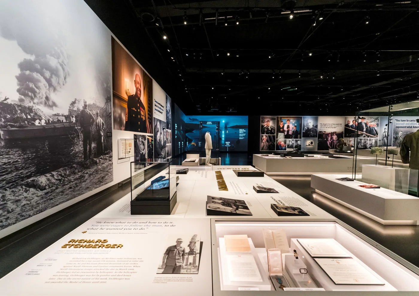 Gallery with historical war photographs on the walls and artifact cases with recipient stories
